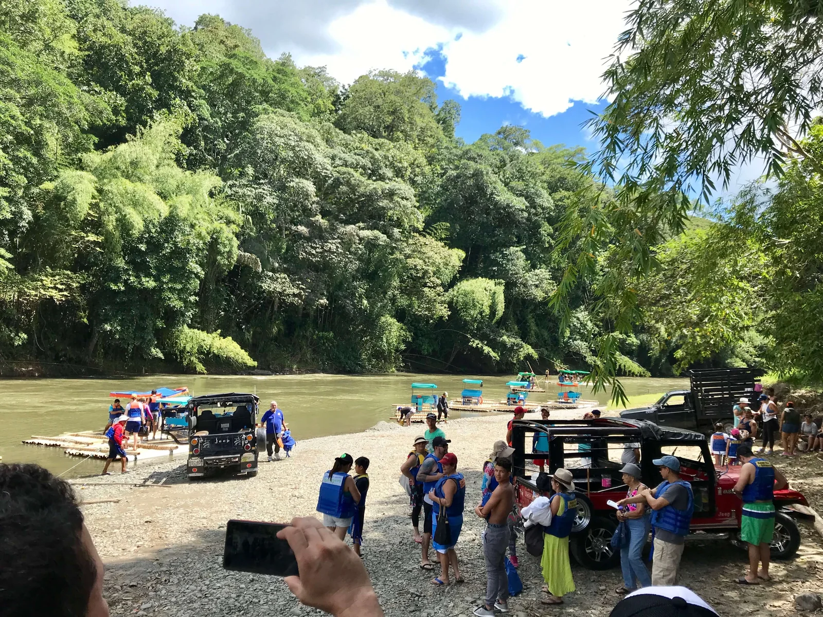 Punto de embarque en la orilla del Río La Vieja con balsas y Jeep Willys
