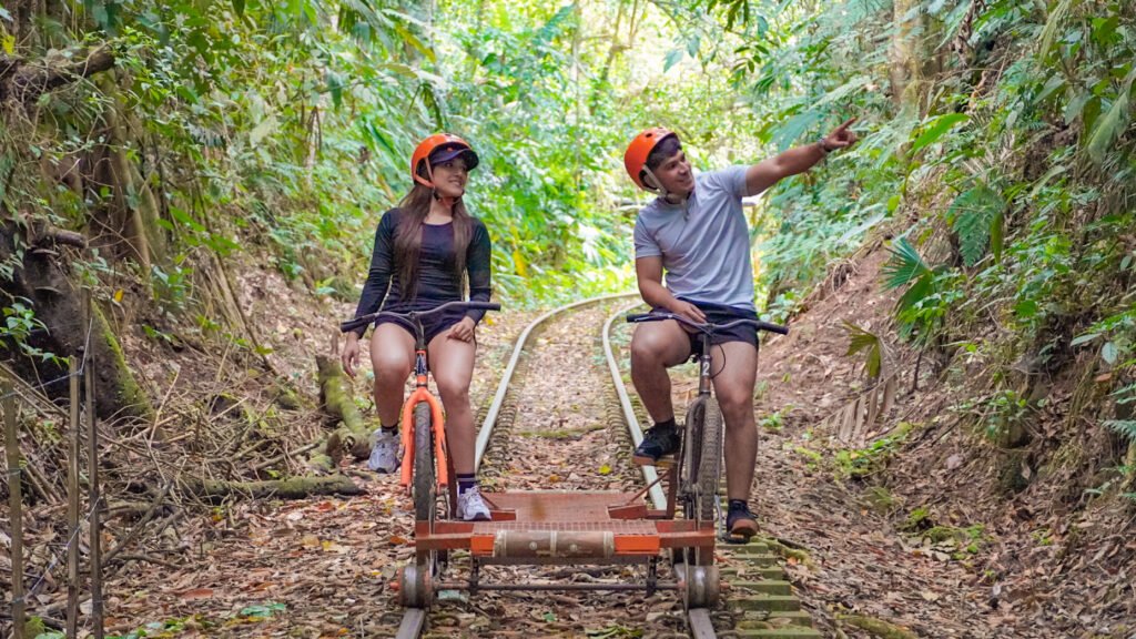 Pareja recorre en Bici-Riel el paisaje verde de La Granja Ecohotel en Quindío.